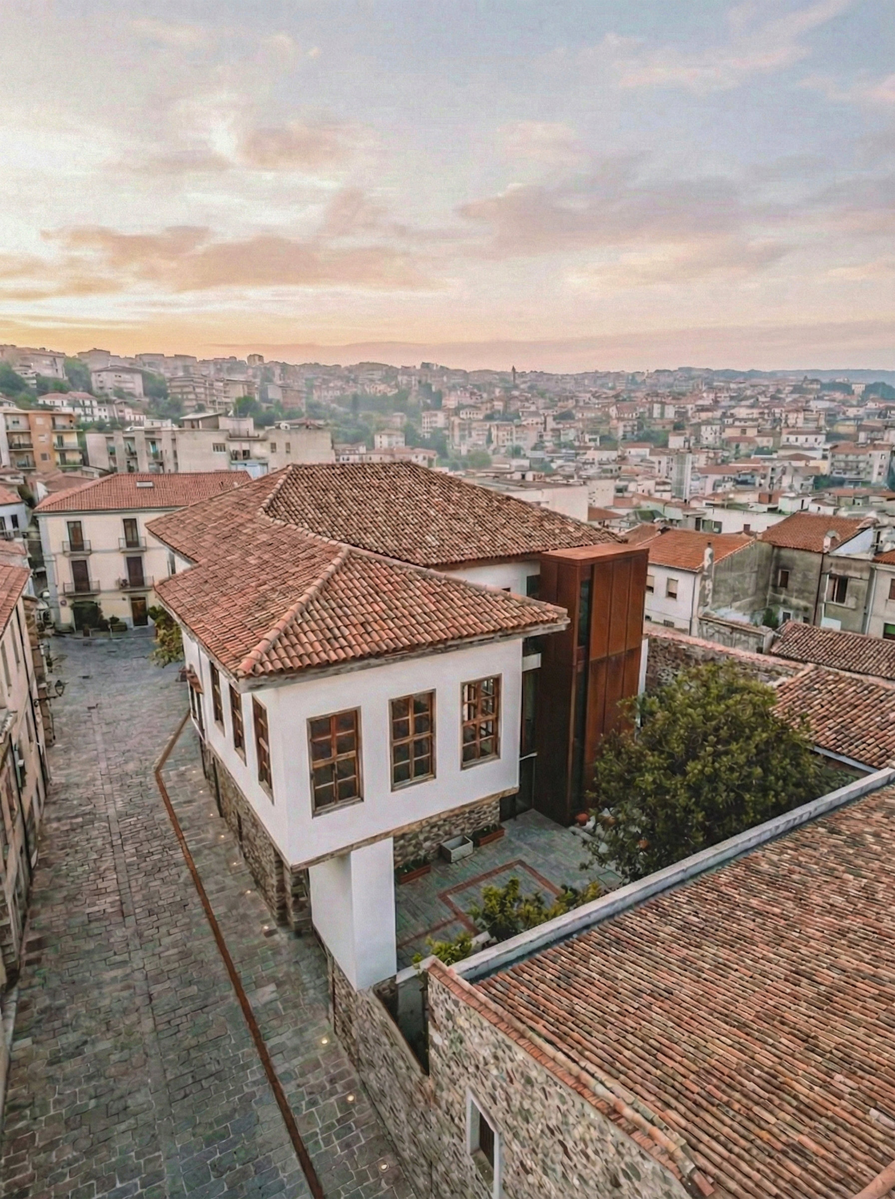Yapının kuş bakışı görünümü; kiremit çatılar, avlu ve Burdur kent silueti